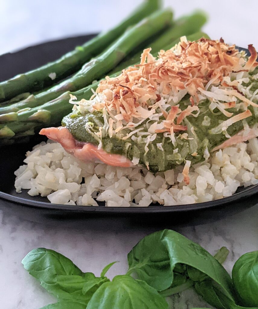 Pesto coconut salmon sitting on top of cauliflower rice, with a side of asparagus.