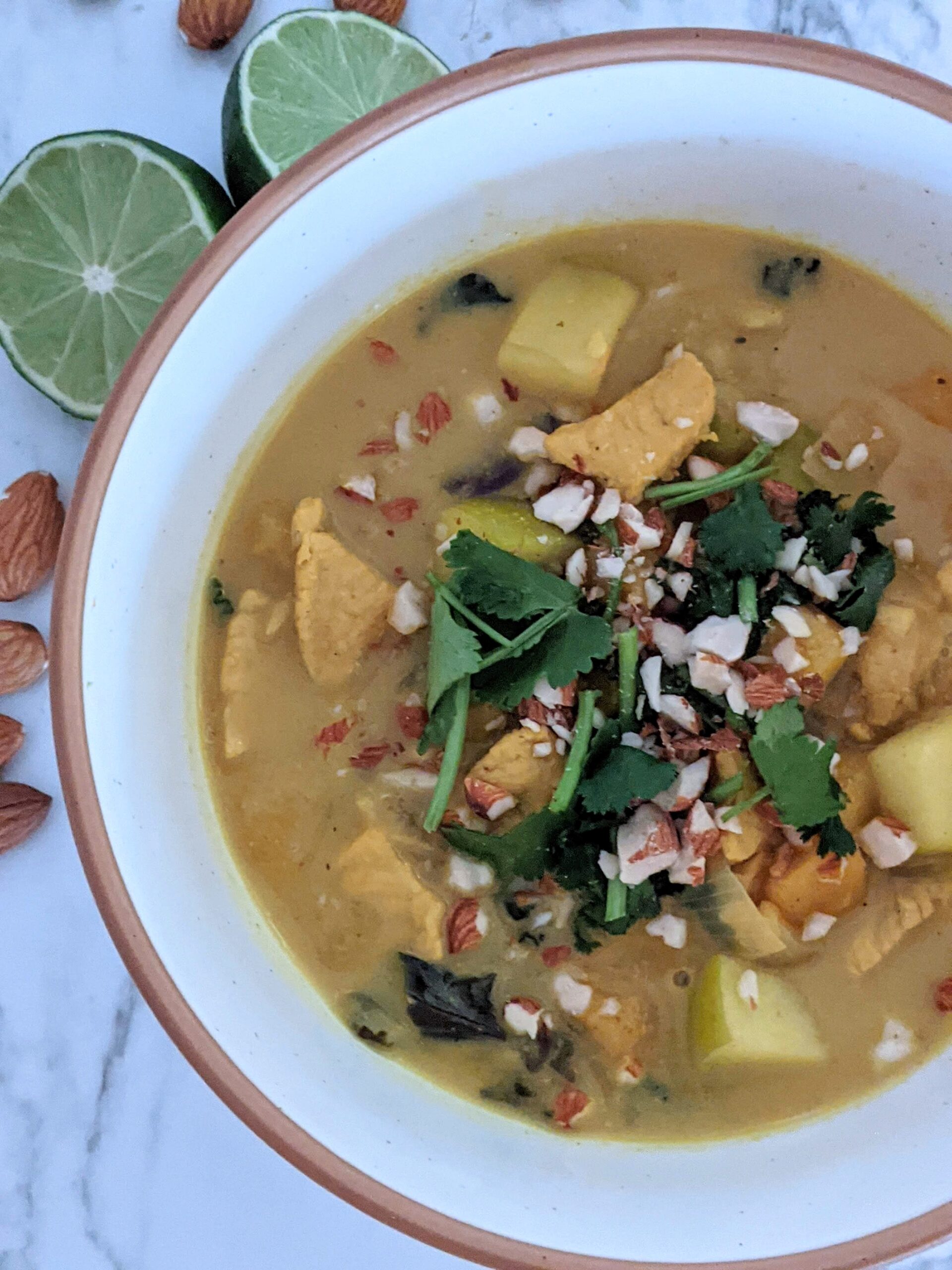 Bowl of curry topped with nuts and cilantro.