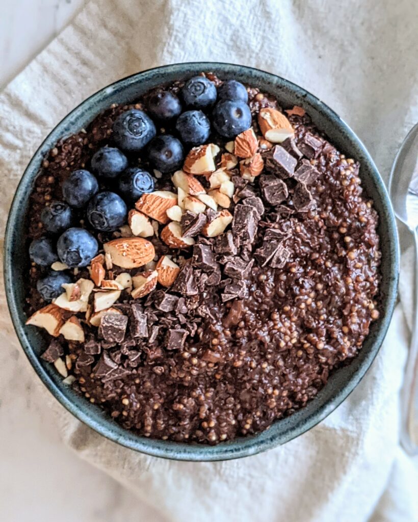 Quinoa bowl topped with blueberries, chopped almonds, and chocolate chunks.