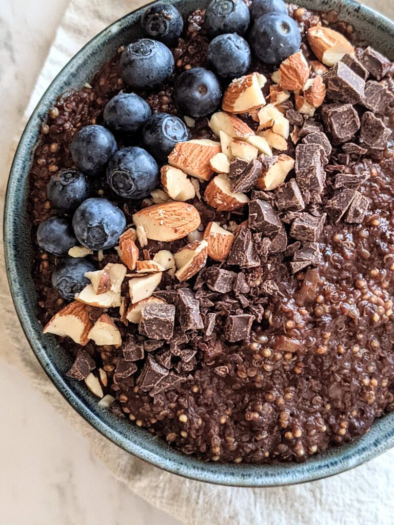 Closeup of the chocolate zucchini quinoa protein bowl topped with blueberries, chopped almonds, and chocolate chunks.