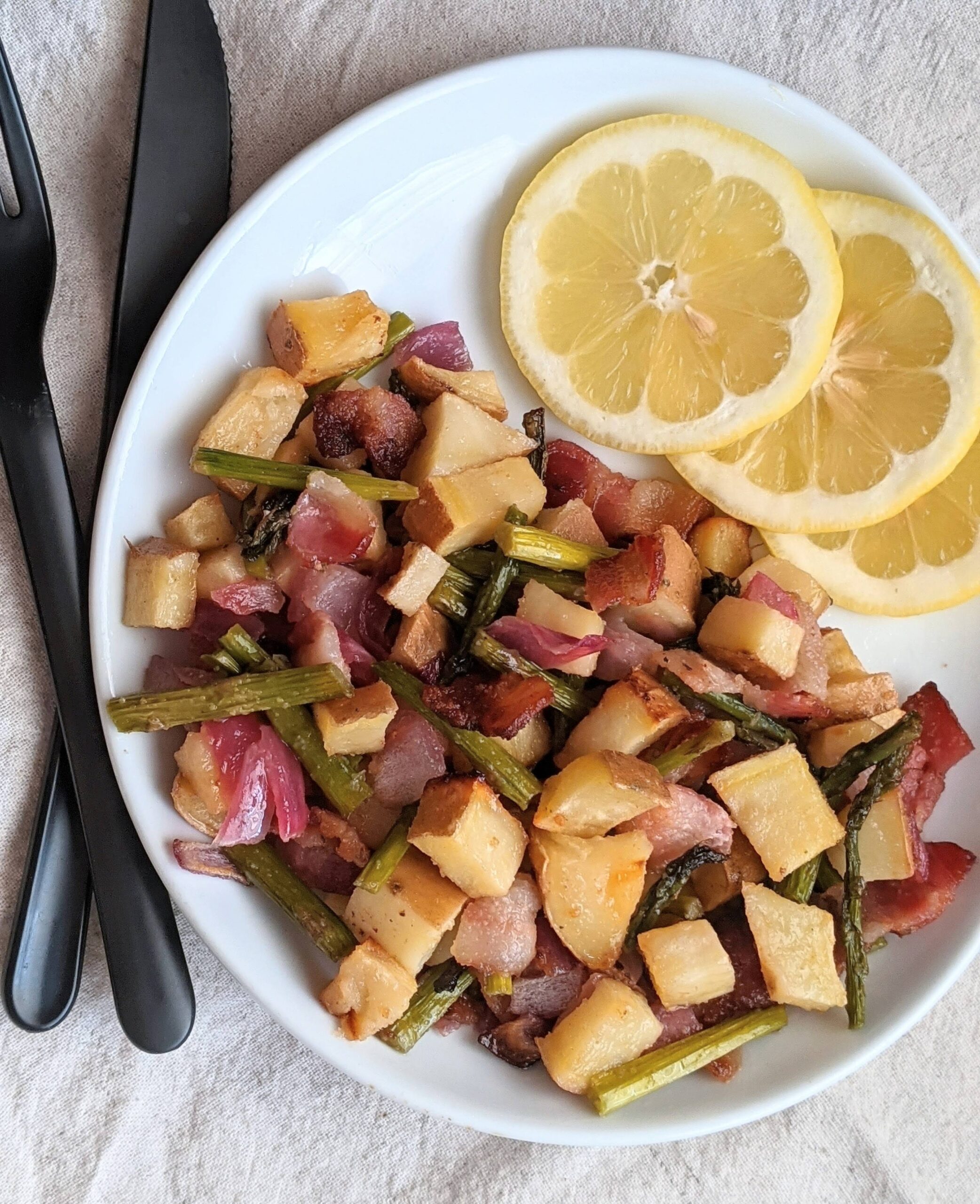 Plate of lemon bacon asparagus with lemons on the side.