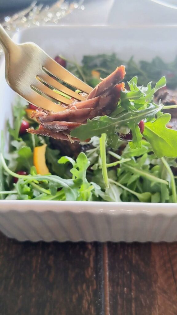 Closeup bite of roast with arugula on the fork.