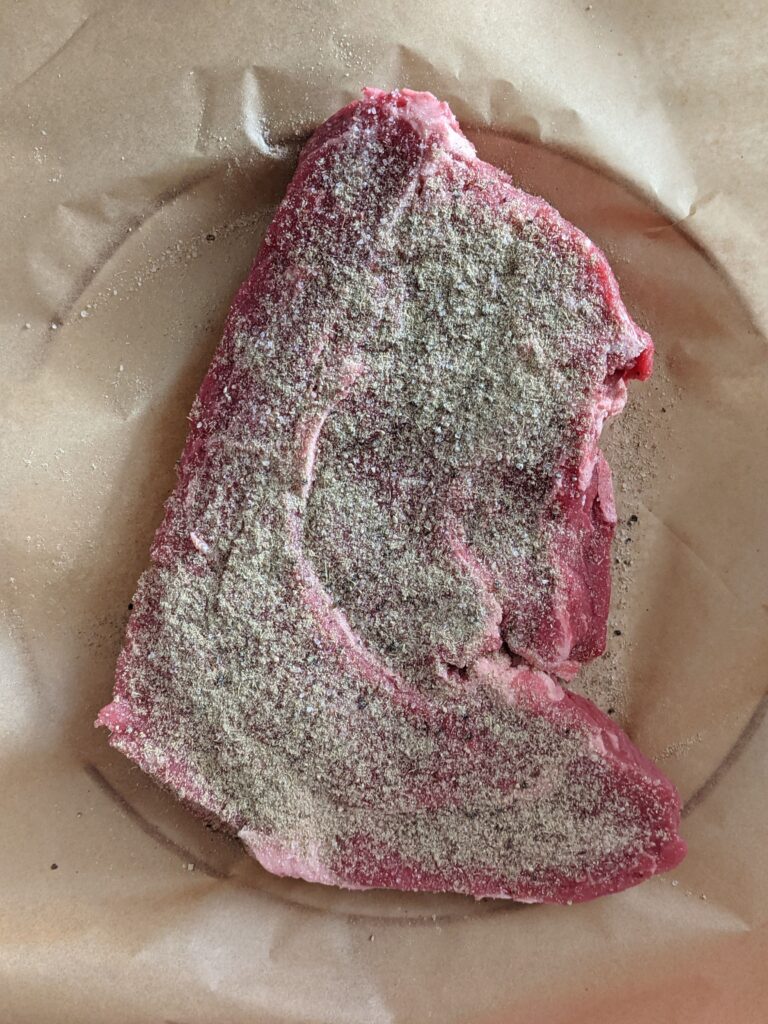 Seasoned raw roast sitting on parchment paper.