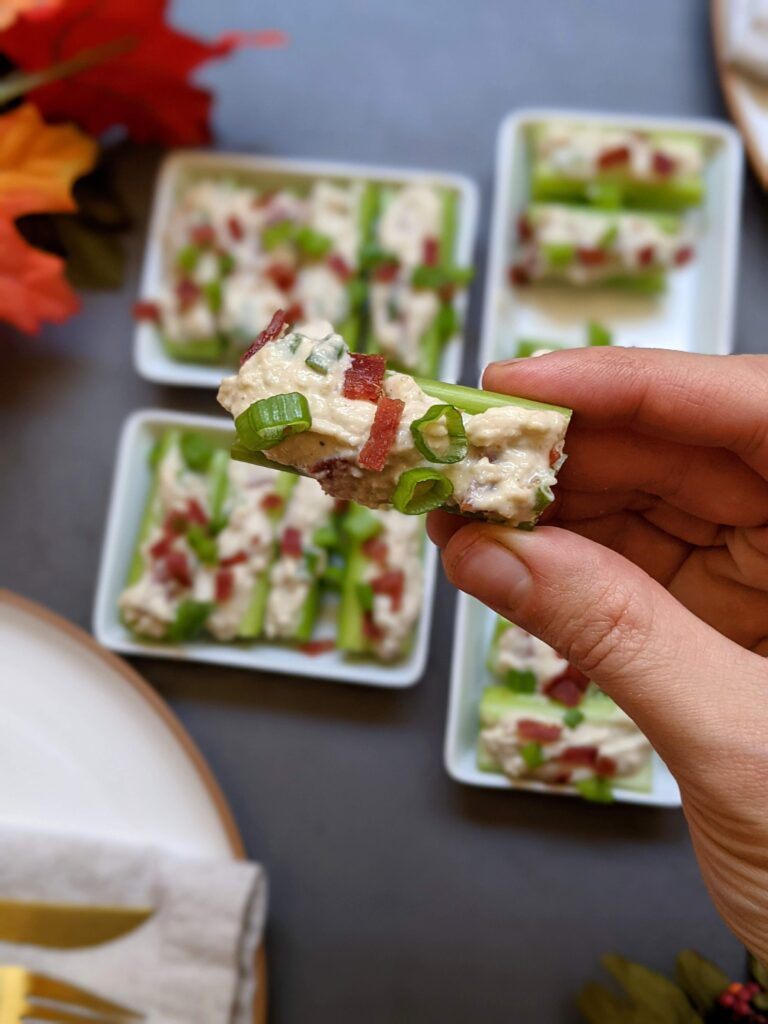 Closeup of a hand holding one of the stuffed celery bites.