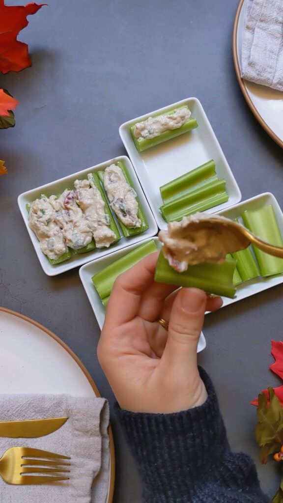 A gold spoon filling a piece of celery with the cashew cream mixture.