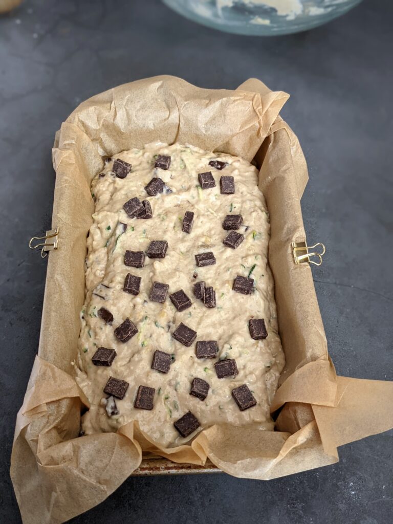 Raw banana bread batter in a parchment lined loaf pan.