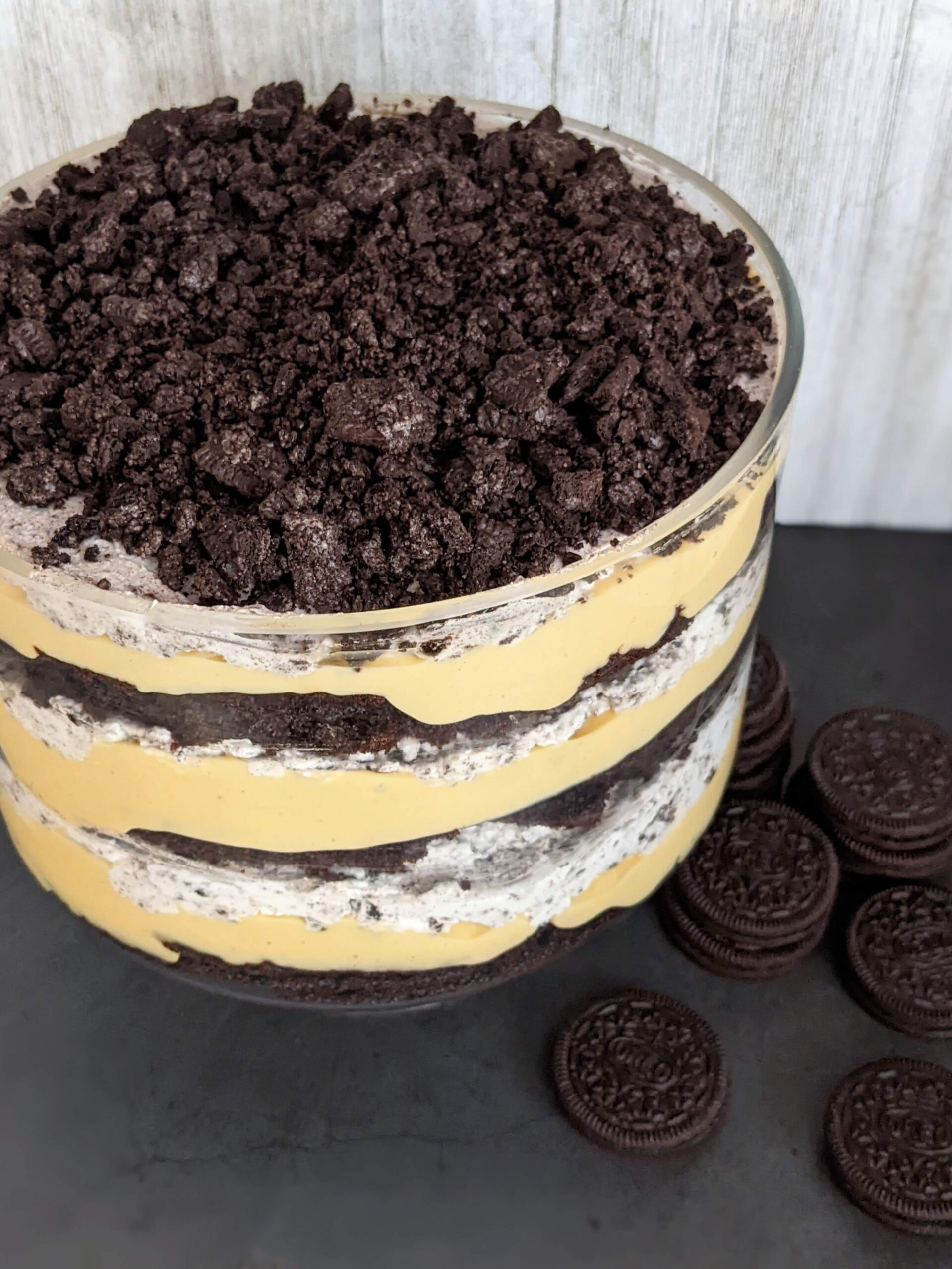 Angled top view of the peanut butter Oreo trifle. Oreo cookies sit in small stacks next to the bowl.