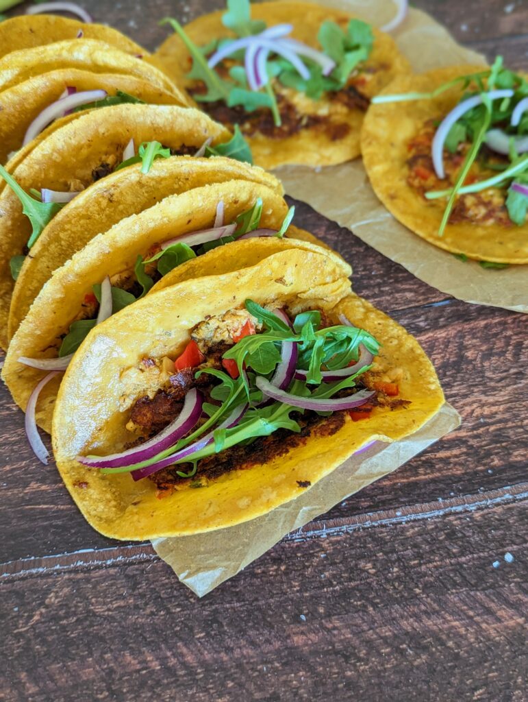 Finished tacos are laid out in a row. This picture is focused on the taco at the end of the row.