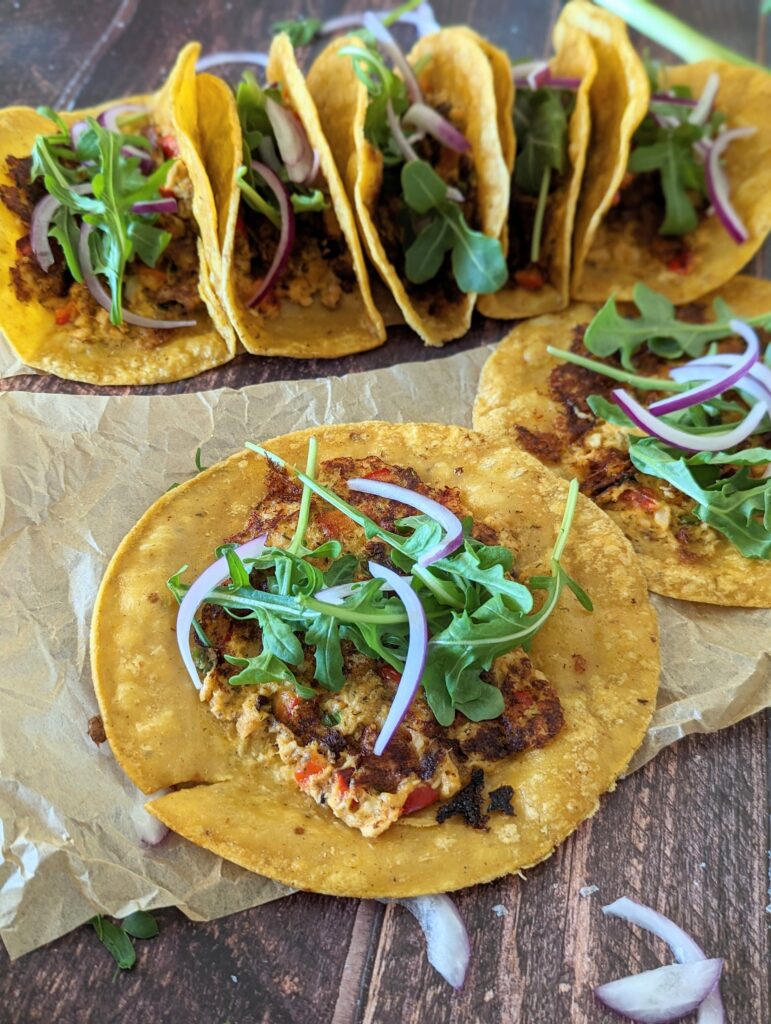 Two smash tacos lie flat, while behind them are the folded tacos in a row.